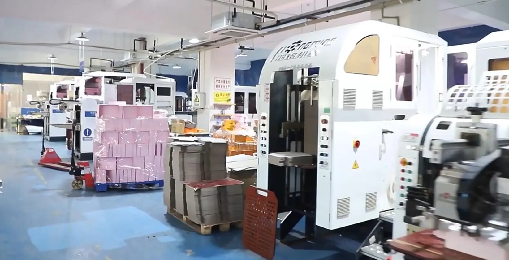 Paper box production workshop with machinery and stacked boxes